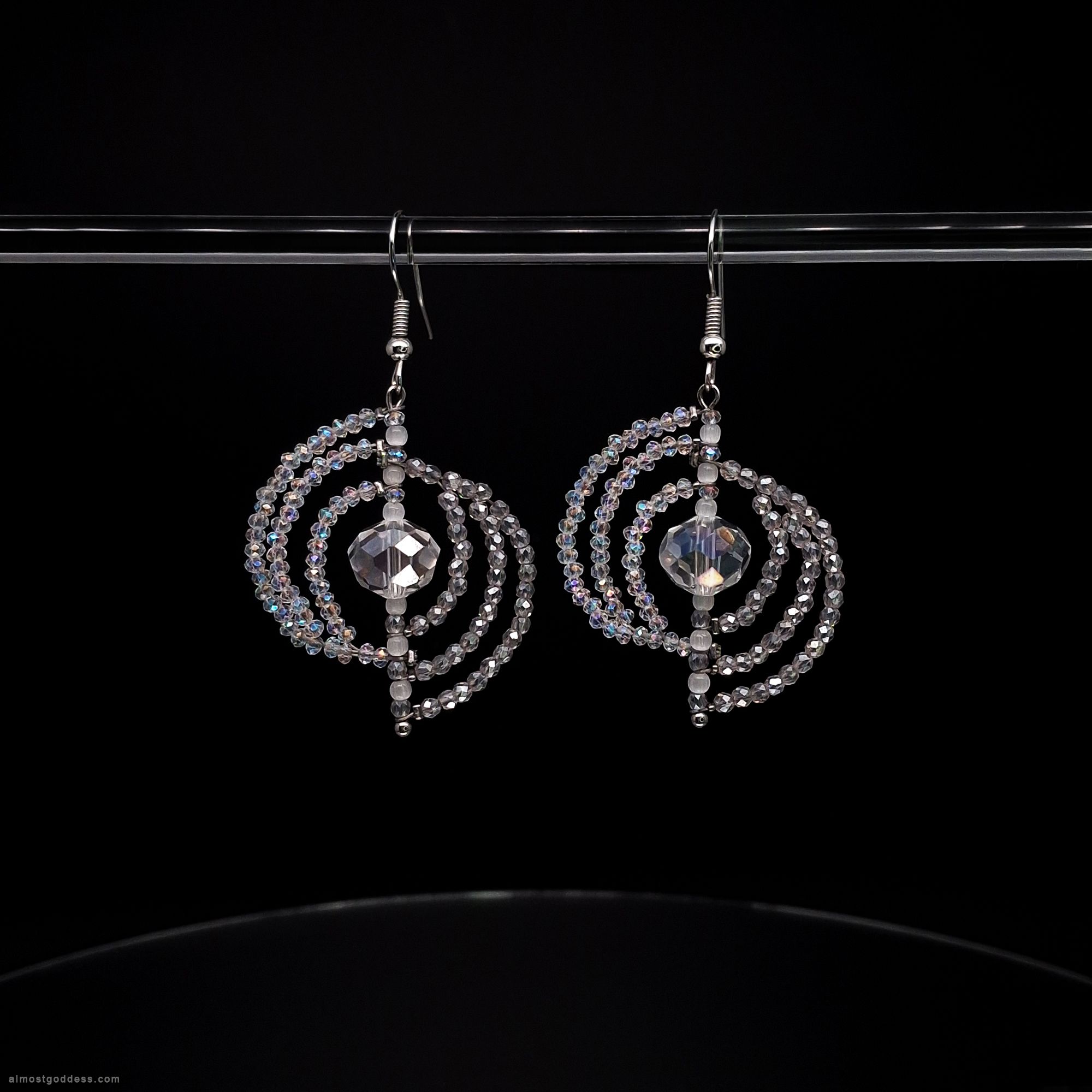 Sparkling silver spiral dangle earrings with clear crystal beads and faceted center stone. Handmade circle drop earrings with iridescent glass beads on fishhook wires for sensitive ears
