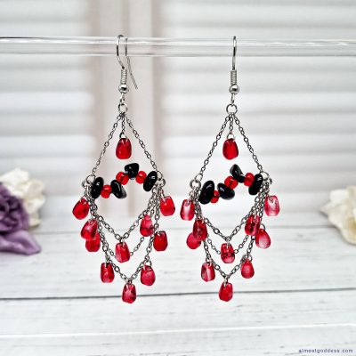 Black and red chandelier dangle earrings with stainless steel chains, glass teardrop beads, and black agate accents. Gothic statement drop earrings with fishhook wires, featuring red and black gemstone-style jewelry for women