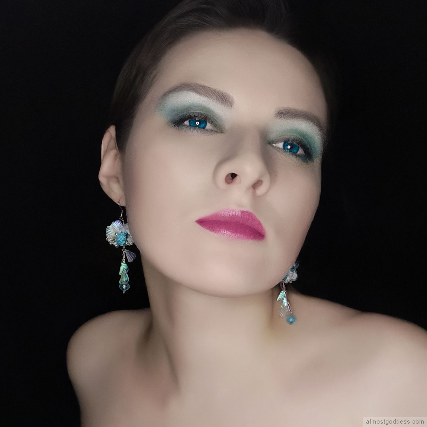 Woman wearing handmade blue and white ocean-themed dangle earrings with beaded embroidery and iridescent shell details. Crystal drop earrings with stainless steel hooks featuring lace and sequin embellishments for sensitive ears