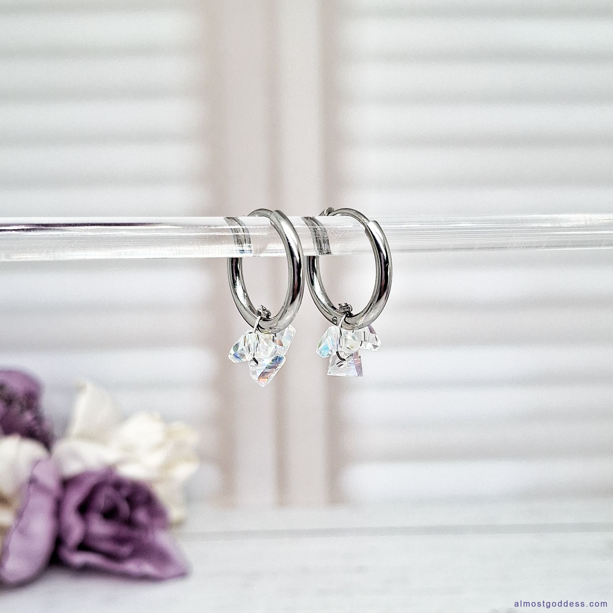 Small stainless steel hinged hoop earrings with dangling clear crystal charms. Hypoallergenic silver-tone huggie hoops with secure closure, suitable for sensitive ears and everyday wear