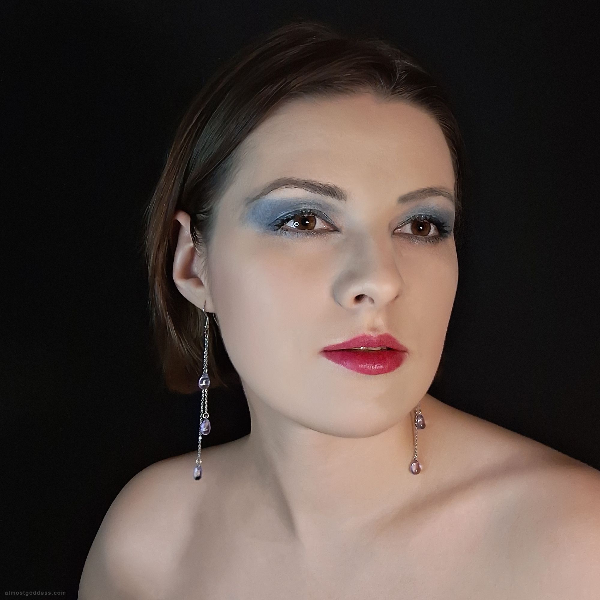 Woman wearing long iridescent teardrop dangle earrings with purple and blue glass beads. Stainless steel chain drop earrings with hypoallergenic fishhook wires, elegant evening jewelry for sensitive ears