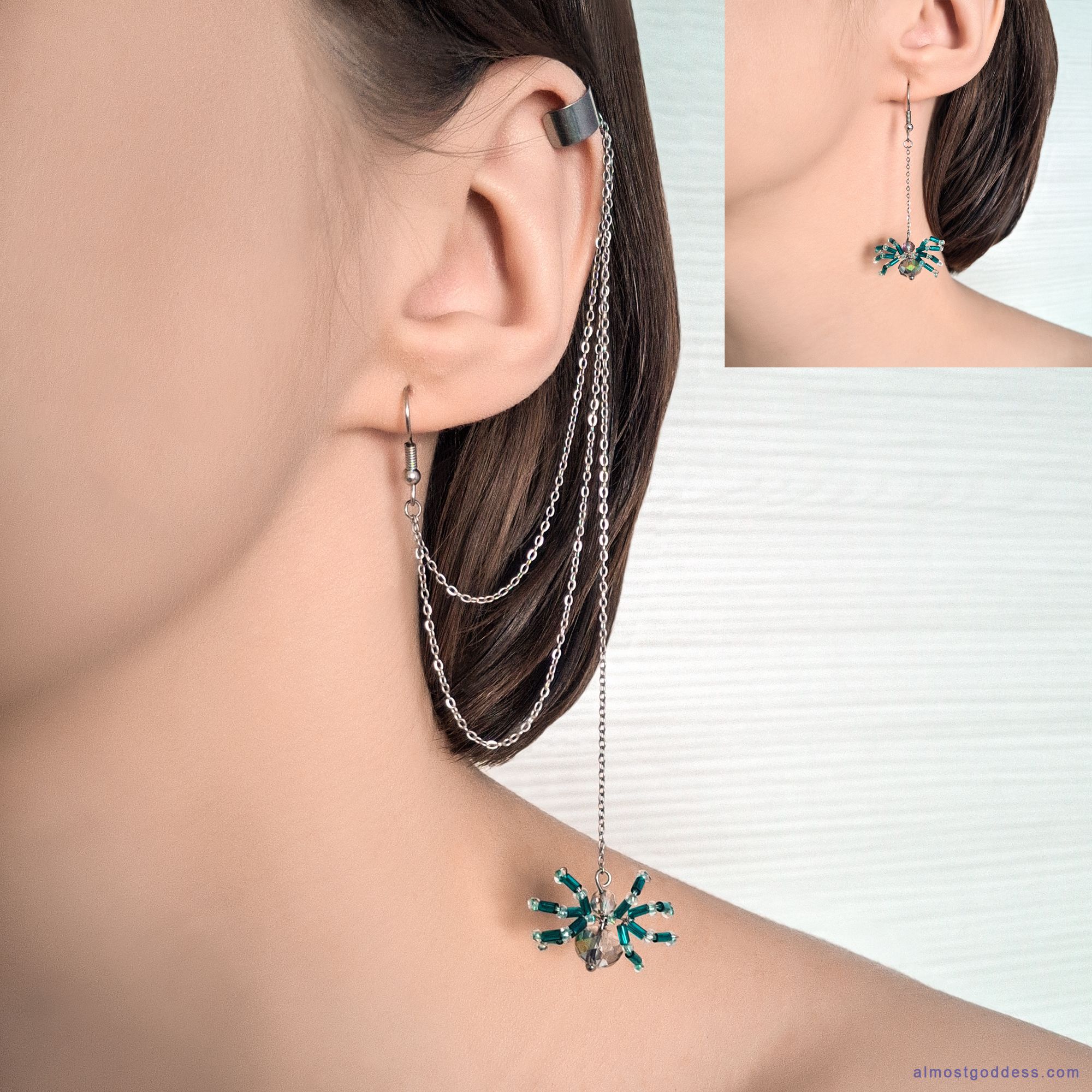 Woman wearing silver ear cuff with long draping chains and green beaded spider dangle earrings. Gothic style asymmetrical jewelry with hanging chains and crystal spider